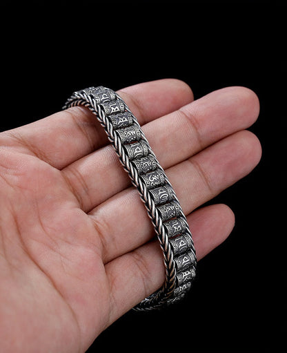 Armbånd med seks tegn som symboliserer sannhetens bønnehjul